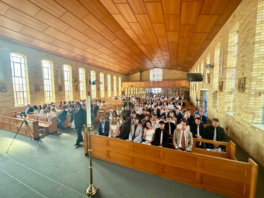 Interior view of a Catholic church during a funeral service, with guests seated in pews, in Sydney.